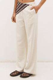 Woman wearing satin-backed linen blend wide leg pants with high-rise fit, scarf waist tie, elasticated back waistband, and relaxed tailored silhouette