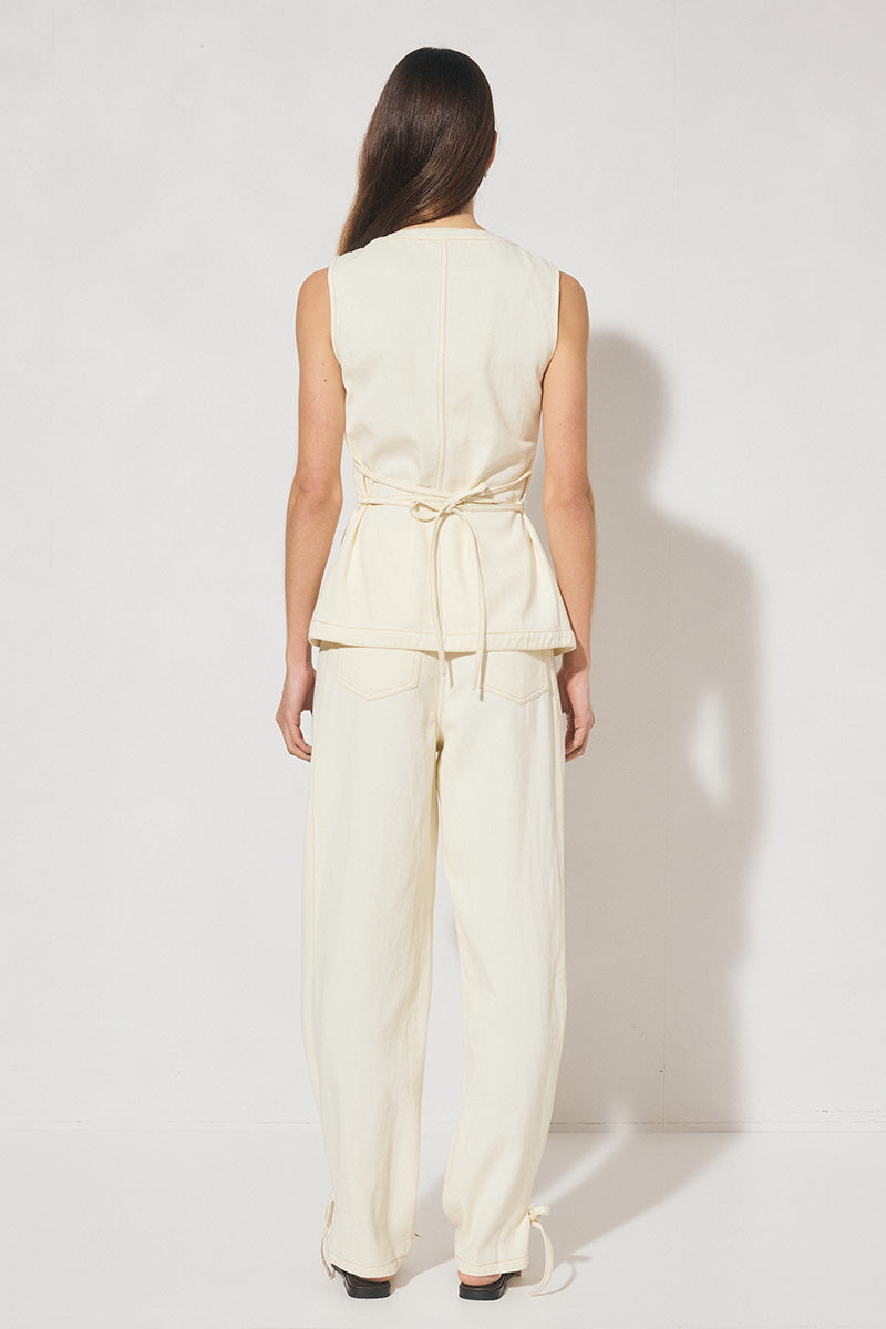 Sleeveless denim longline vest top with V neckline, pintucked waist, back tie, curved front hem, banded edges, and contrast topstitching