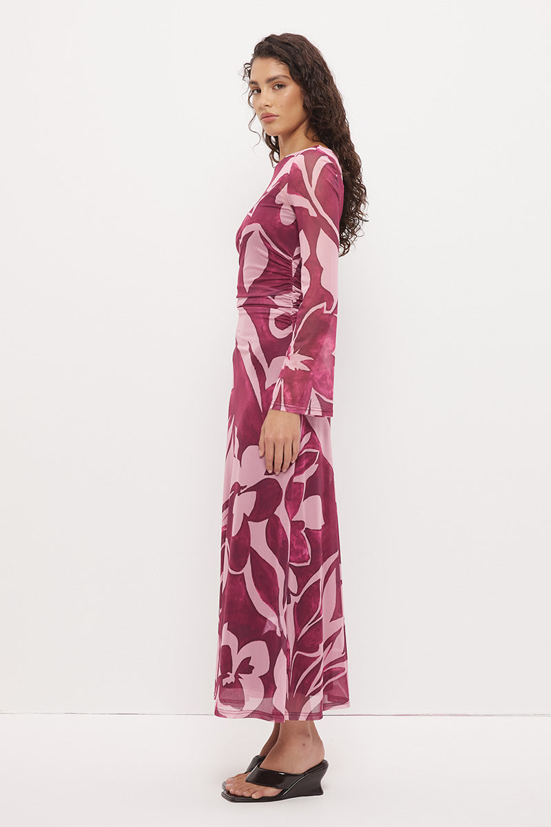 Woman wearing a sheer maxi dress with an exclusive placement print, fit-and-flare silhouette, flared long sleeves, ruched waistline, and a separate full-length slip.