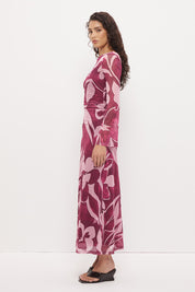 Woman wearing a sheer maxi dress with an exclusive placement print, fit-and-flare silhouette, flared long sleeves, ruched waistline, and a separate full-length slip.