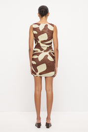 Sleeveless fitted mini dress with boat neckline, side ruching and sarong tie overlay in exclusive handcrafted print