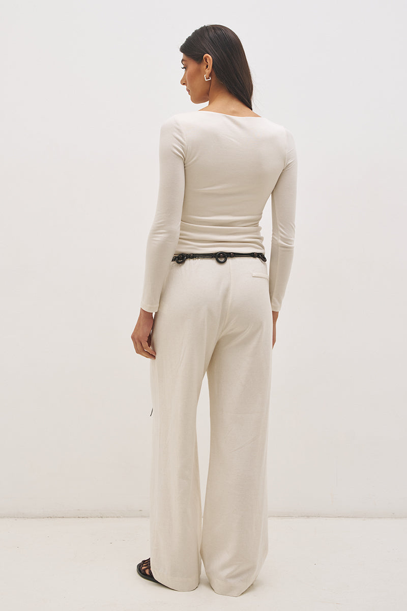 Woman wearing jersey knit long sleeve top with spiral ring neckline, plunging V neck, cascading ruching, and skimming fit silhouette