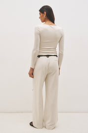 Woman wearing jersey knit long sleeve top with spiral ring neckline, plunging V neck, cascading ruching, and skimming fit silhouette