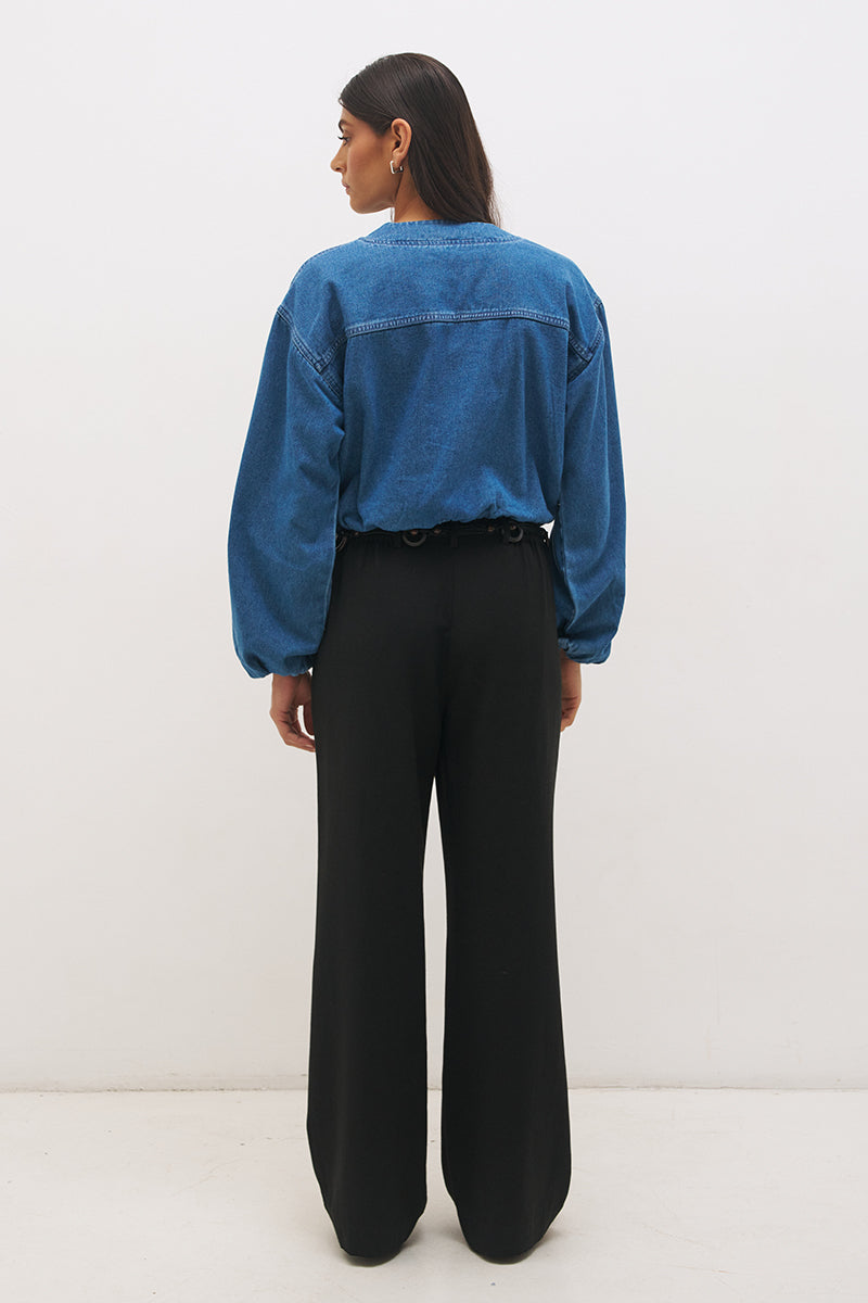 Woman wearing a washed denim bomber jacket with a stand collar, wide dropped shoulders, long balloon sleeves, bubble hem, and metal zip closure.