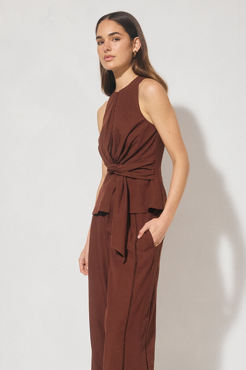 Sleeveless textured woven top with crew neckline, ladder trim detail, twisted waist sash, and side seam splits