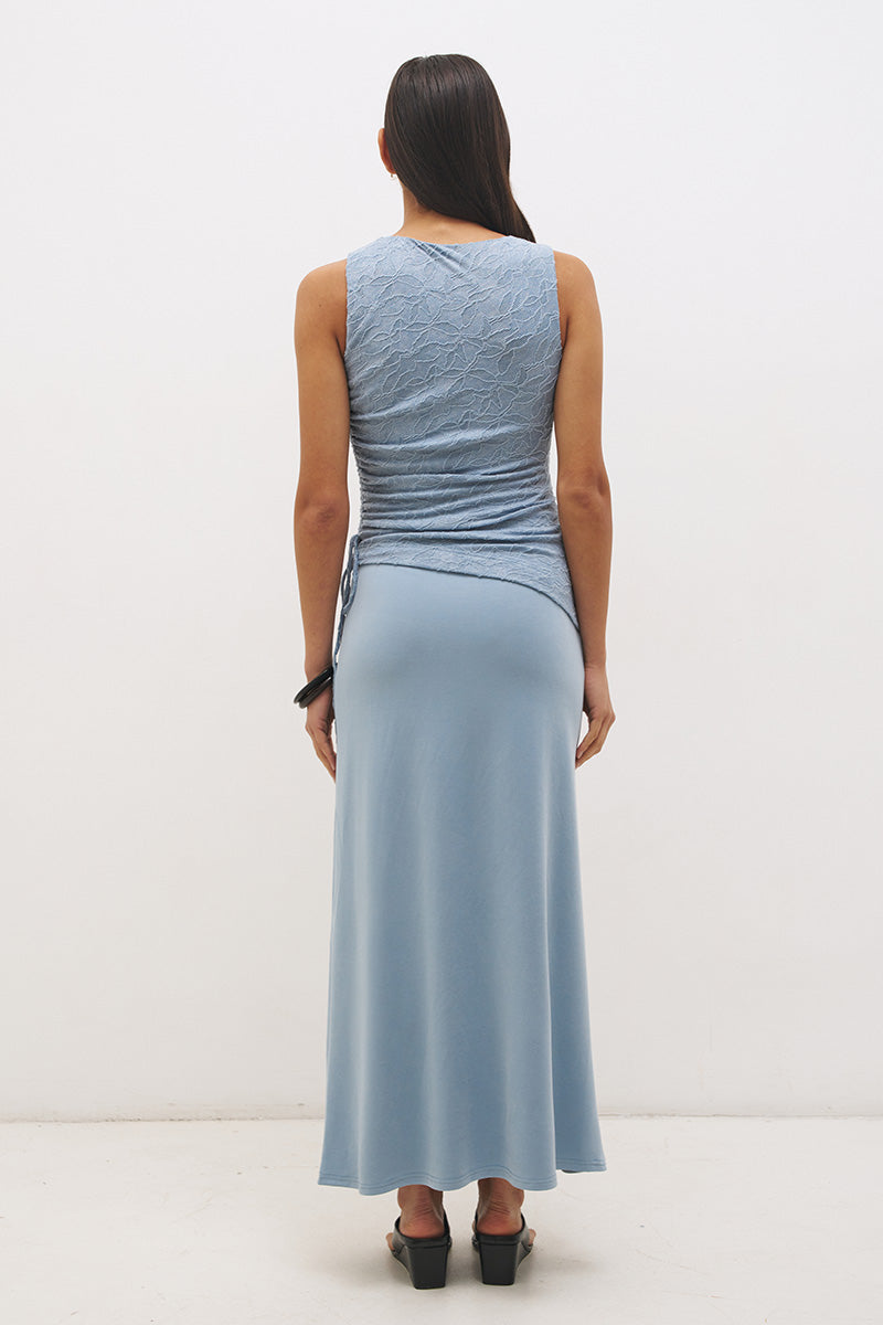 Woman wearing a sleeveless maxi dress with a textured lace bodice overlay, sunray ruching, boat neckline, and a contrast smooth A-line modal skirt in a fit-and-flare silhouette.
