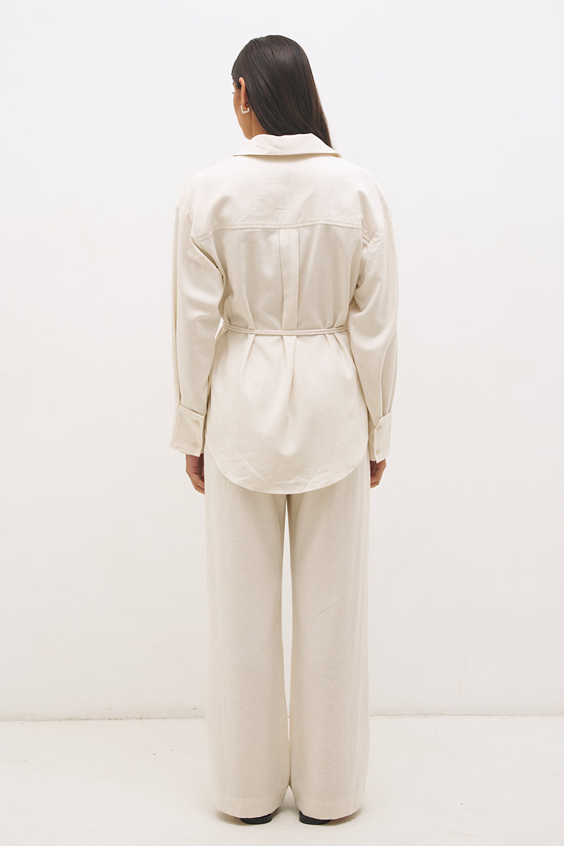 Woman wearing a satin-backed linen blend longline tunic with V neckline, curved hem, relaxed fit, and removable waist tie