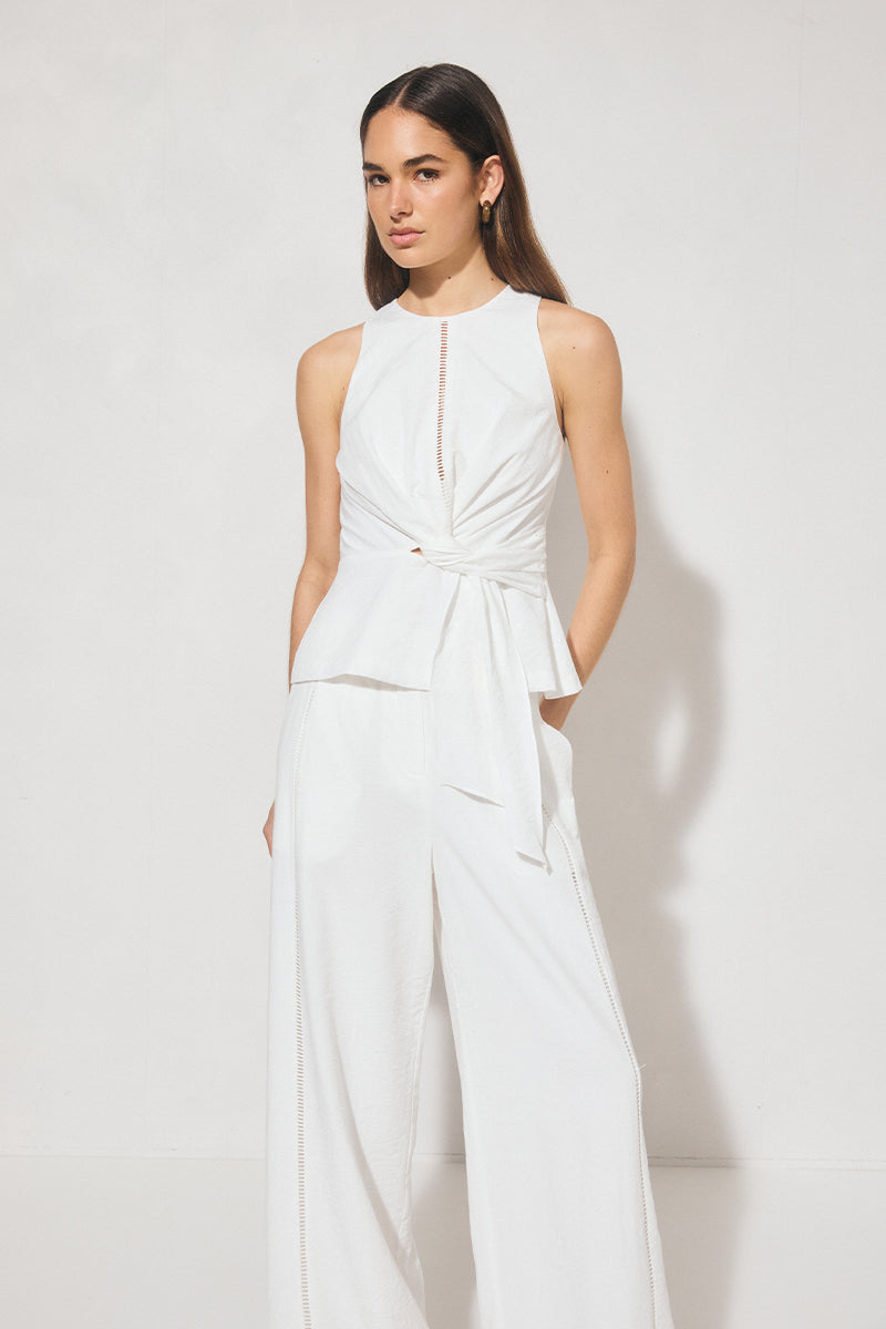 Sleeveless textured woven top with crew neckline, ladder trim detail, twisted waist sash, and side seam splits