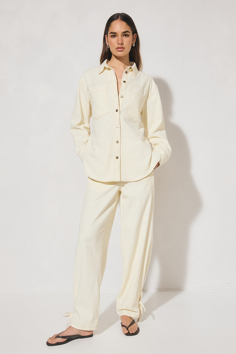 Long-sleeved oversized denim shirt with dropped shoulders, collar & stand, back box-pleat, back waist tie, chest patch pockets, side hem splits, and contrast topstitching