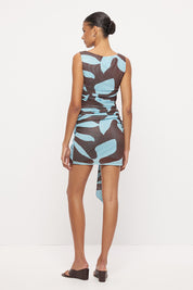 Sleeveless fitted mini dress with boat neckline, side ruching and sarong tie overlay in exclusive handcrafted print