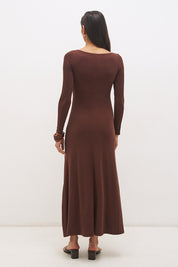 Woman wearing a textured cupro jersey long sleeve midi dress with boat neckline, cascading ruching, fit-and-flare silhouette, and draped A-line hem