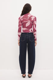 Woman wearing a semi-sheer long sleeve top in stretch ribbed mesh with an exclusive placement print, funnel neckline, centre front chest ruching, and lettuce hem finishes.