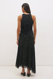 Woman wearing a printed polka dot mesh sleeveless midi dress with a draped cowl neckline, fit-and-flare silhouette, ruched drawcord waist, and asymmetric hi-lo raw-cut hem.