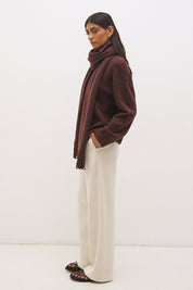 Woman wearing oversized scarf knit jumper with removable tassel scarf, crew neckline, ribbed trims, and relaxed silhouette