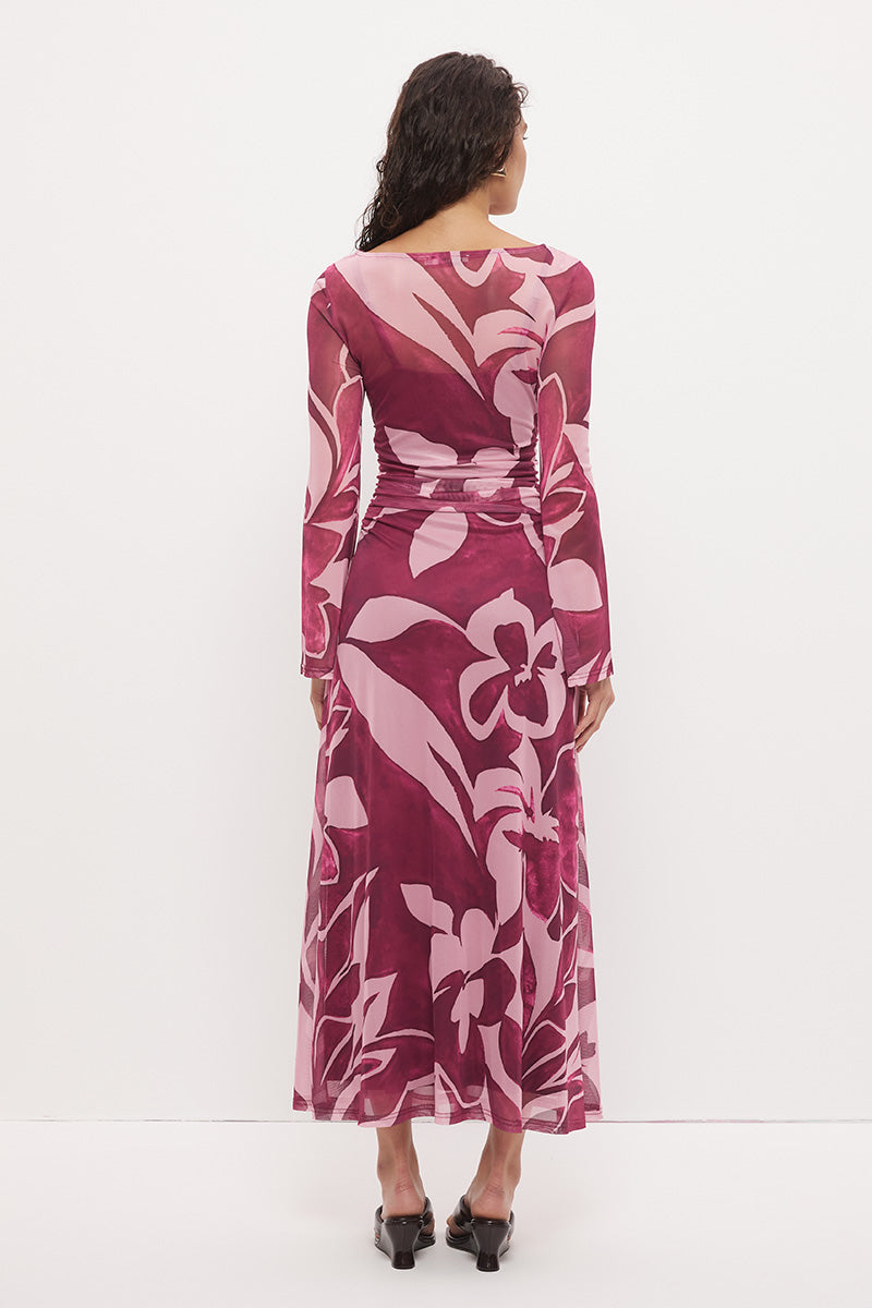 Woman wearing a sheer maxi dress with an exclusive placement print, fit-and-flare silhouette, flared long sleeves, ruched waistline, and a separate full-length slip.