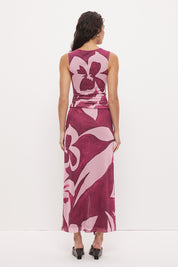 Woman wearing a sleeveless maxi dress with an exclusive placement print, sarong-style wrap skirt overlay, ruched asymmetric waistband, and boat neckline in a softly A-lined silhouette